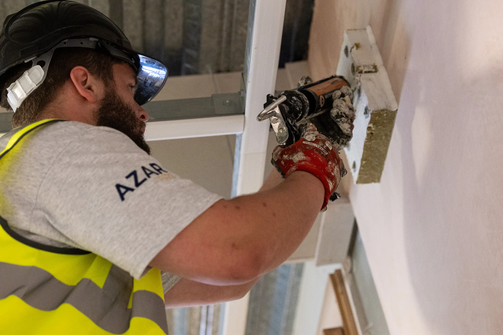 Azar Fire installer applying fire-stopping sealant to a service penetration