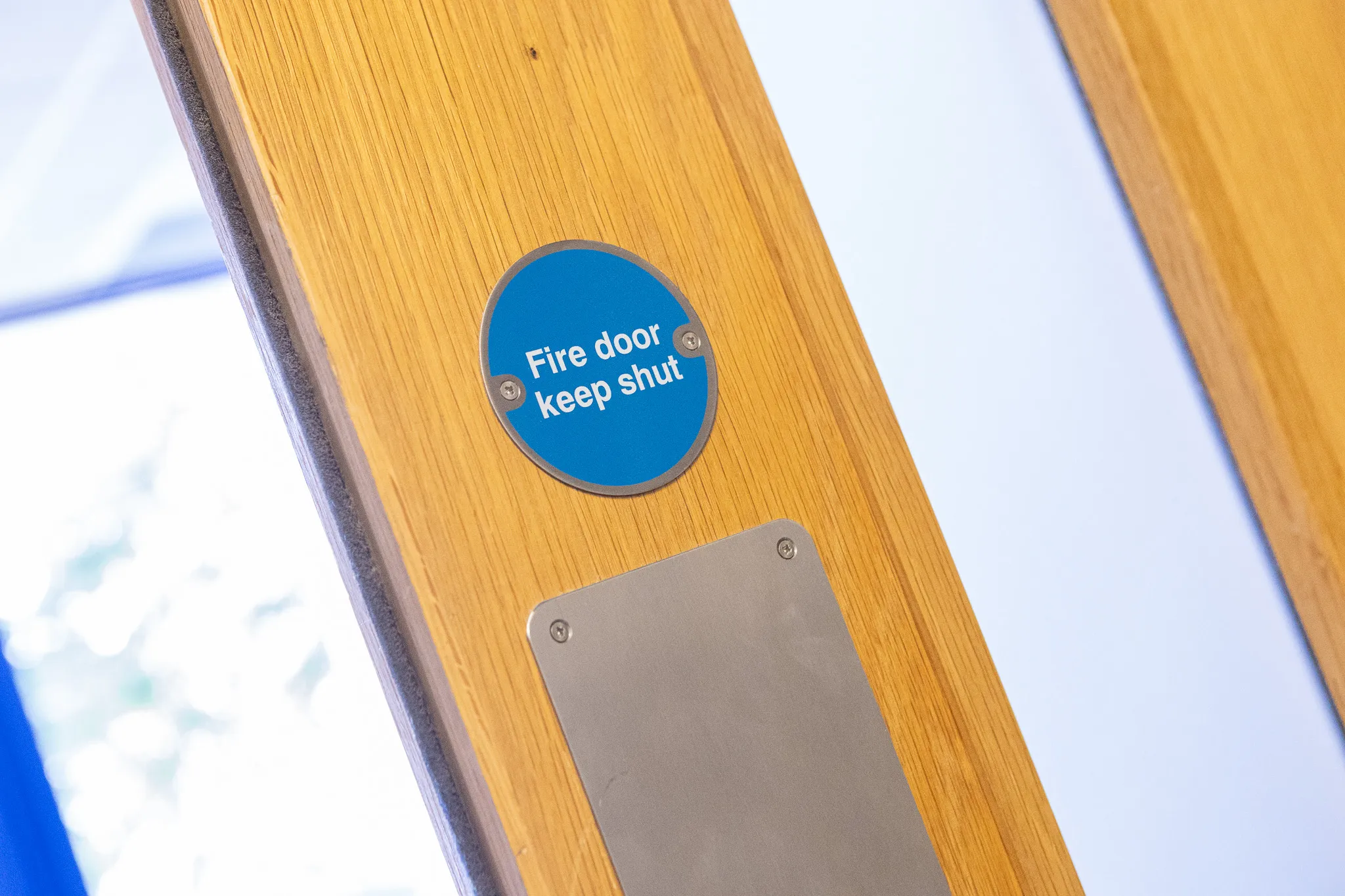 A 'Fire door keep shut' sign on a timber fire door