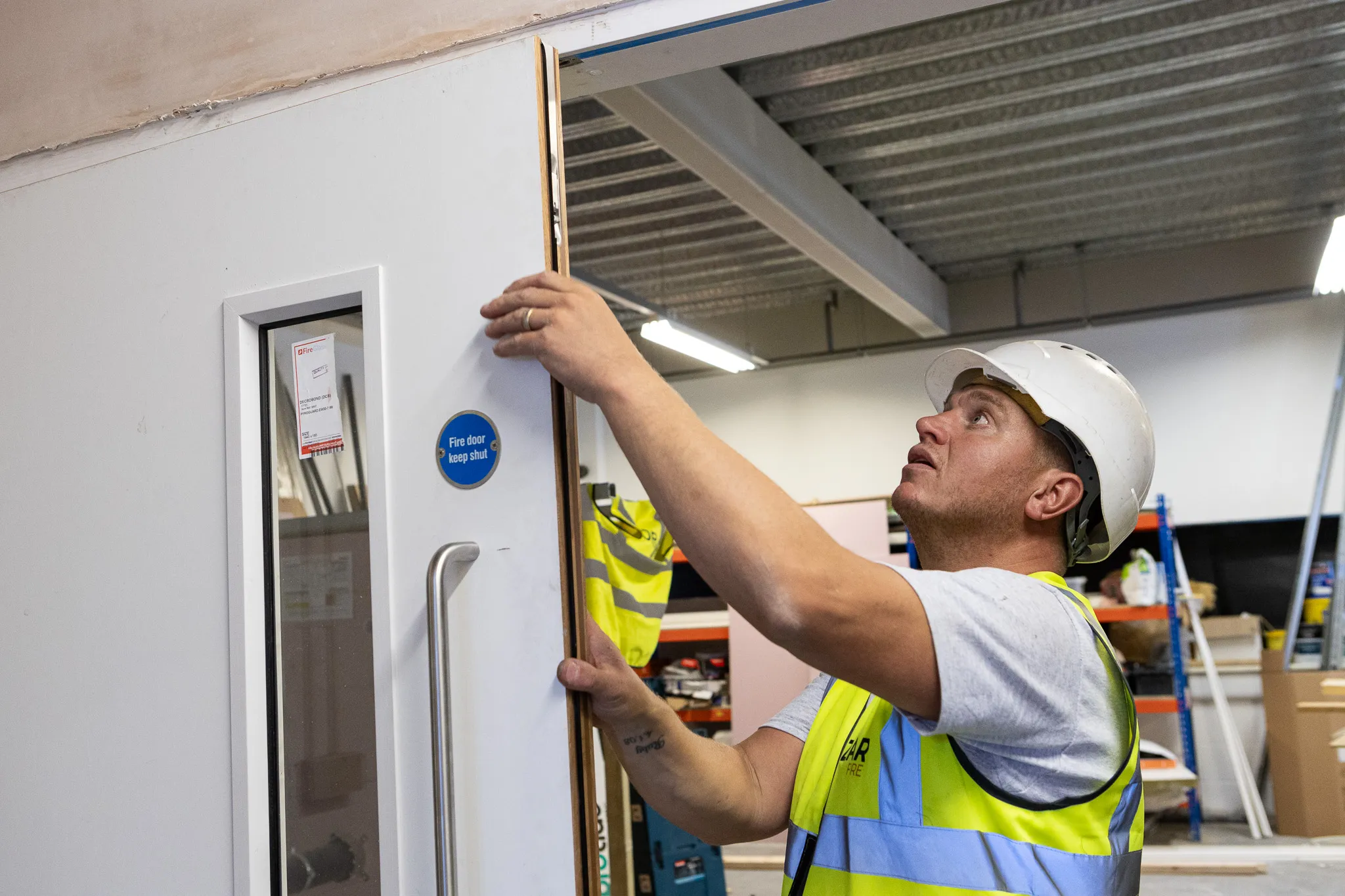 Azar Fire operative inspecting a fire door during a maintenance check
